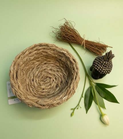 Vetiver Bowl from nature eco products, a handcrafted woven vetiver bowl displayed with dried vetiver roots, green leaves, and a decorative Buddha accent on a soft green background.